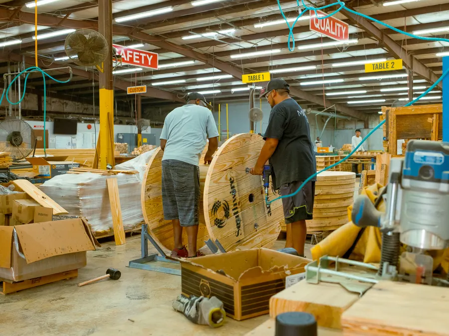 Two employees assembling a large custom wooden cable reel