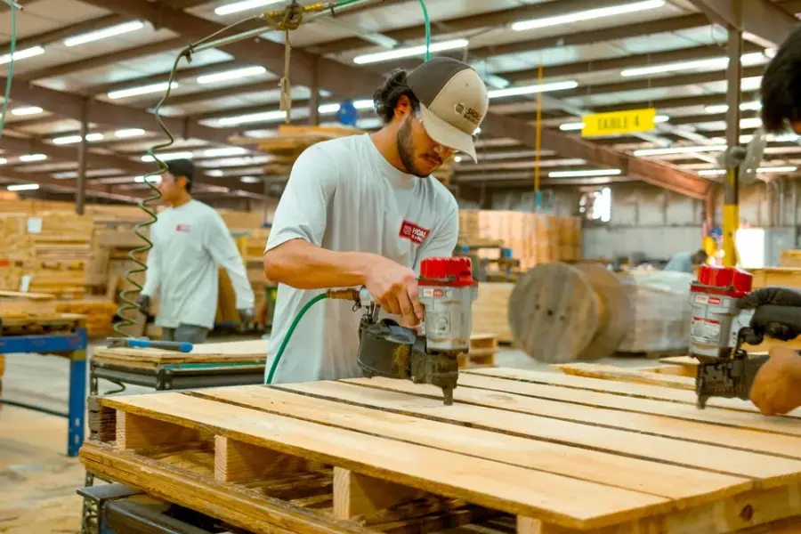 A builder nailing a custom pallet deck on the shop floor